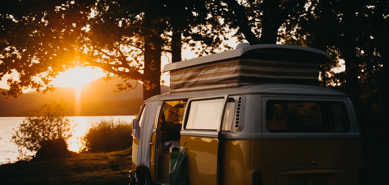A campervan parked beside a lake at sunset