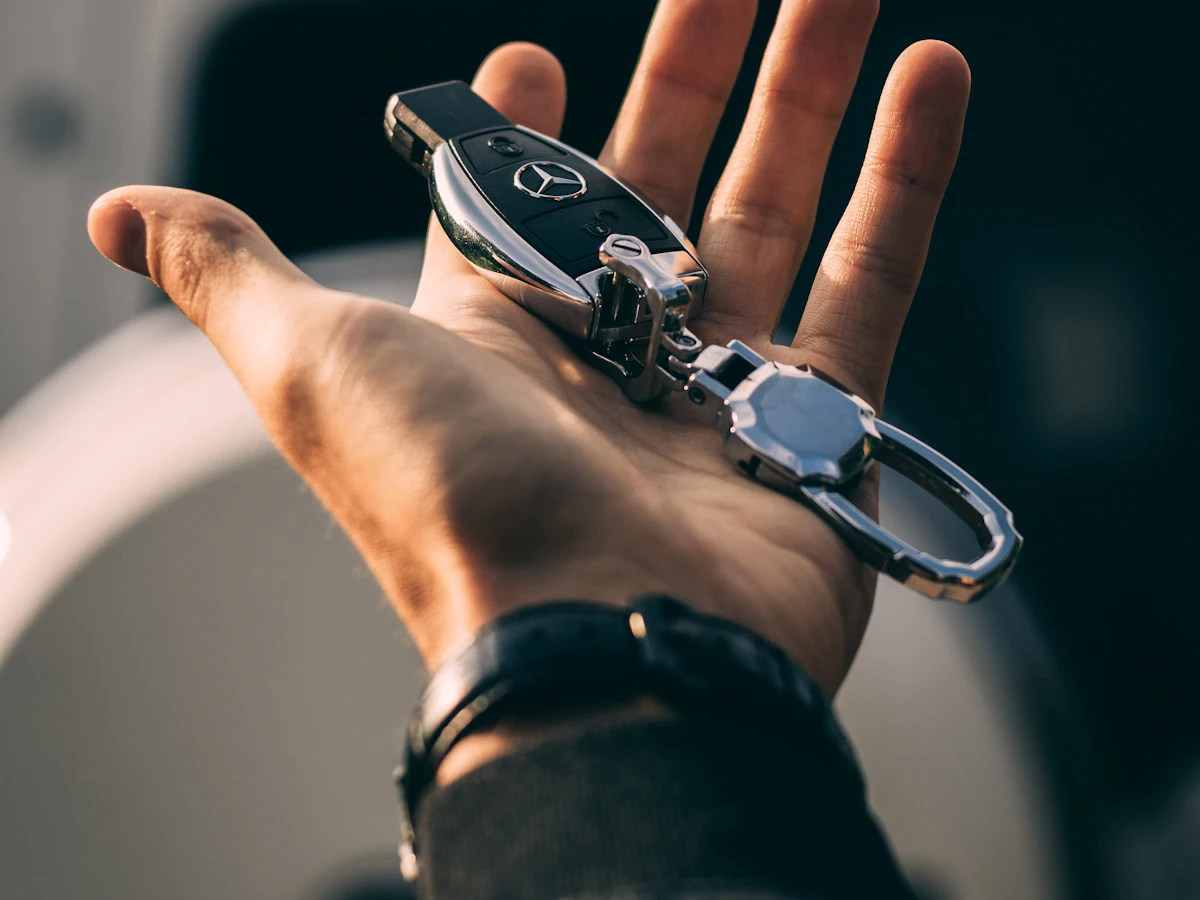 A hand holding car keys, ready to hand over to a rental customer